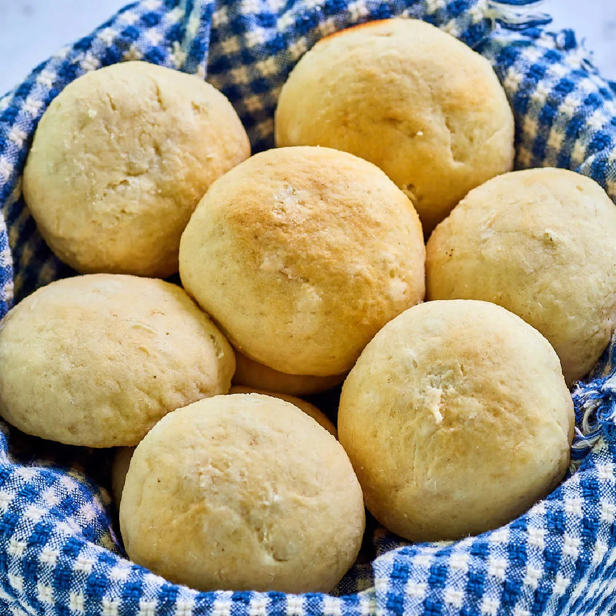 Close up of basket of homemade potato rolls showing their round shape and buttery golden brown tops.
