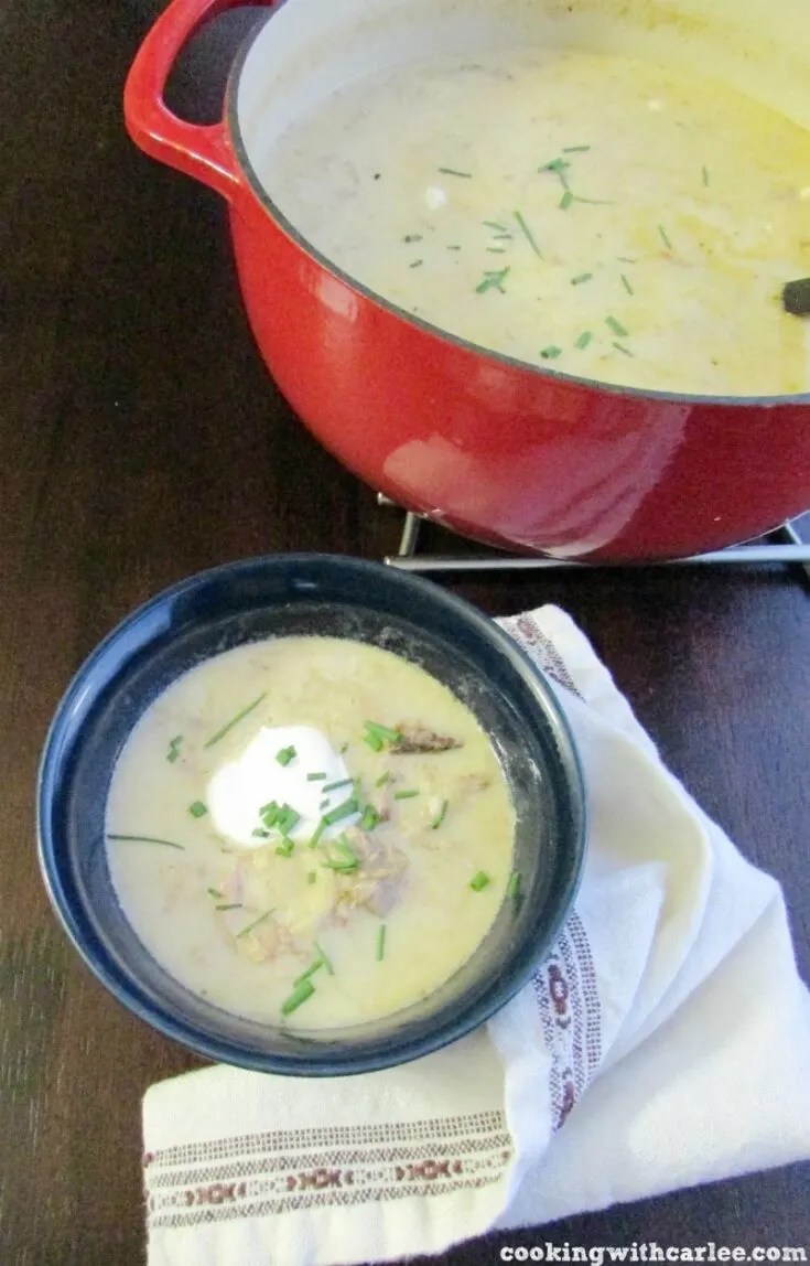 Bowl of creamy pork enchilada soup topped with sour cream and chives.