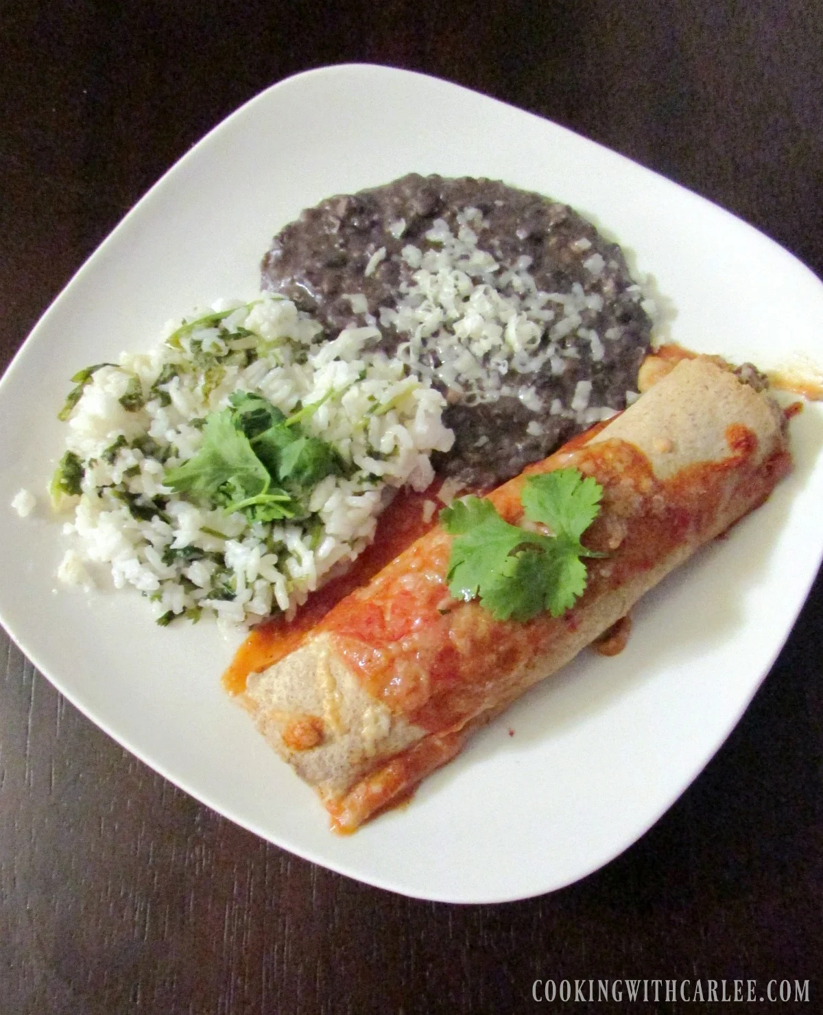 Dinner plate with chicken enchilada, refried black beans and Mexican rice.