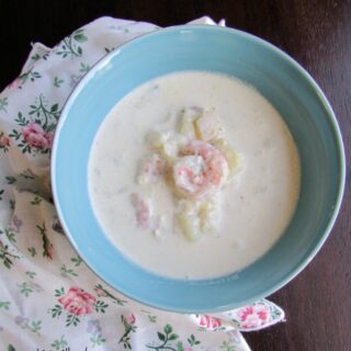 Bowl of creamy seafood chowder with shrimp and fish, ready to eat.