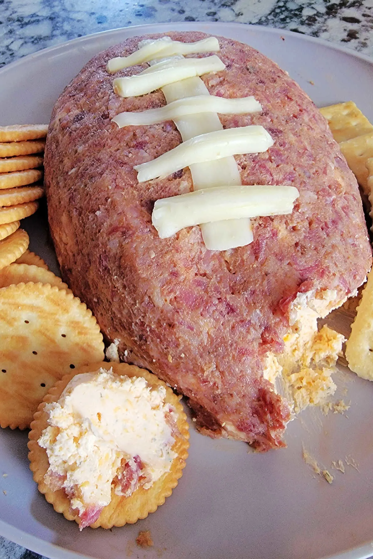 Football shaped cheese ball coated in ground up bacon with string cheese laces.