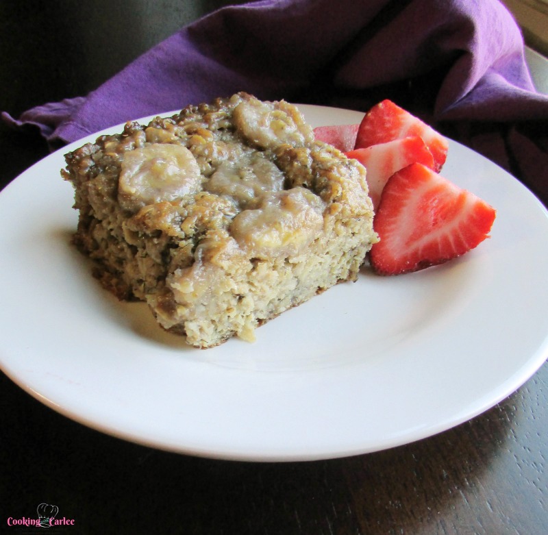 Piece of banana foster baked oats served with fresh strawberries.