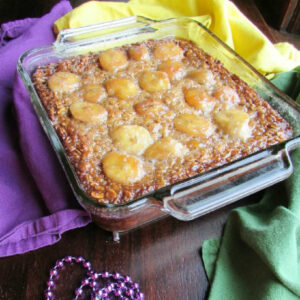 Square baking dish filled with banana baked oats topped with bananas and brown sugar mixture.