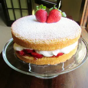 whole victoria sponge cake with strawberries and whipped cream filling.