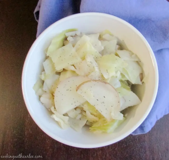 bowl of cooked cabbage with slices of potatoes in it, ready to eat. 