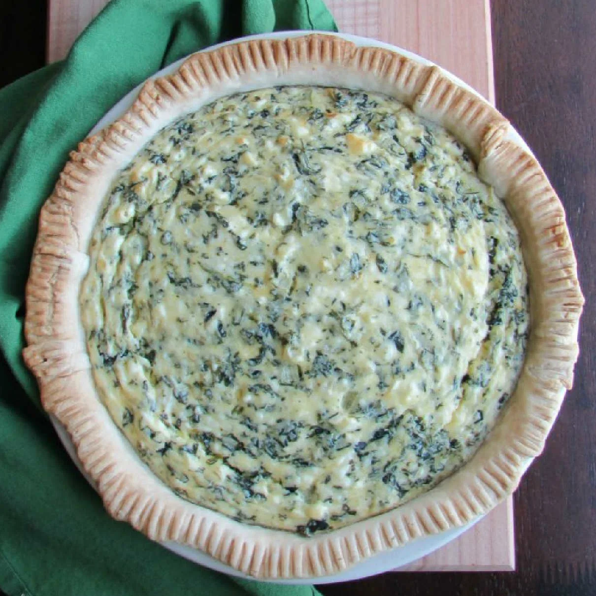 whole pie with golden crust and flecks of spinach in creamy filling.