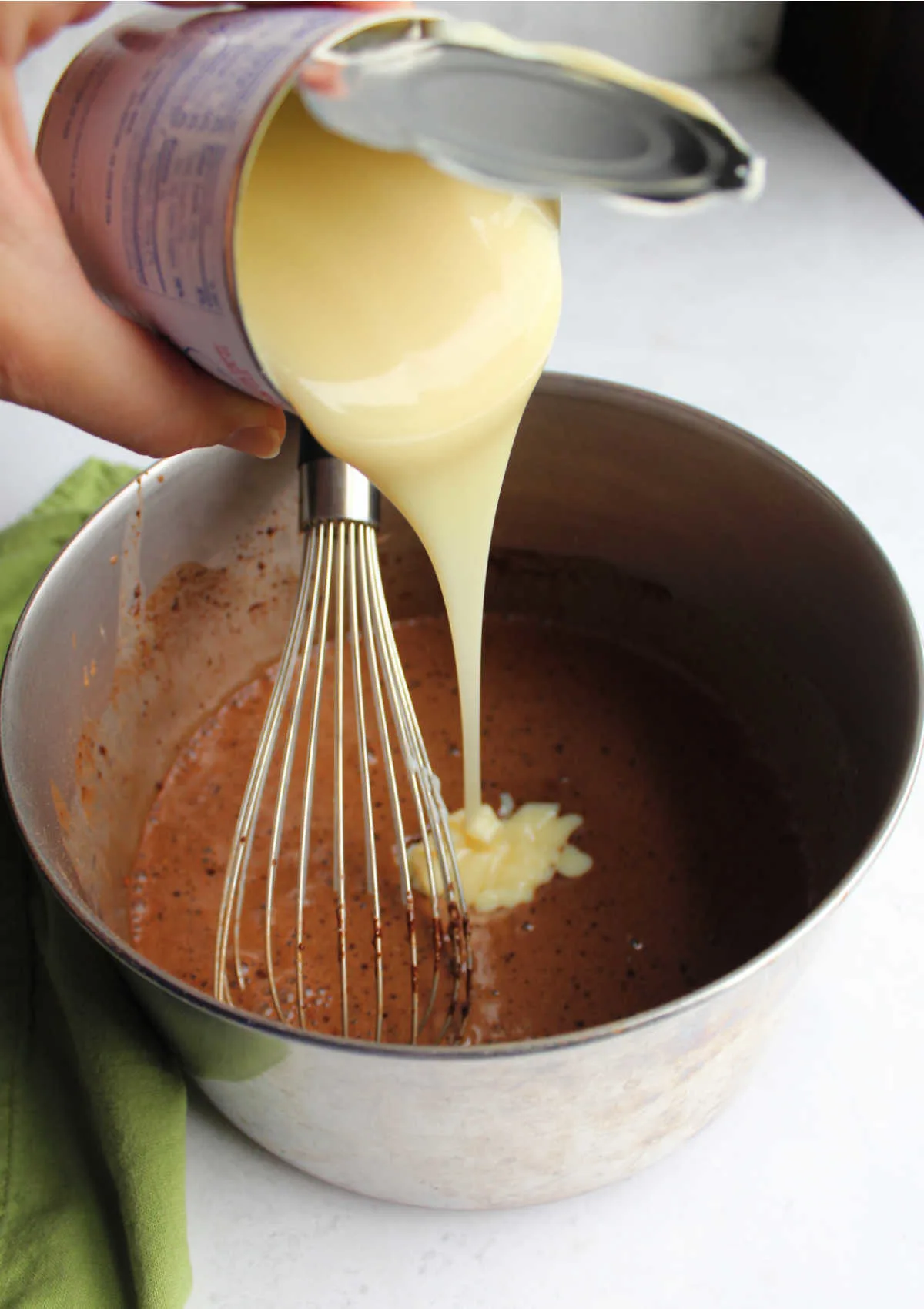 Pouring can of condensed milk into chocolate pudding pie filling mixture.
