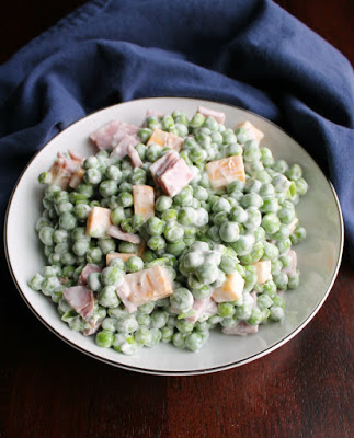 serving bowl filled with creamy pea salad with chunks of ham and cheese in it.
