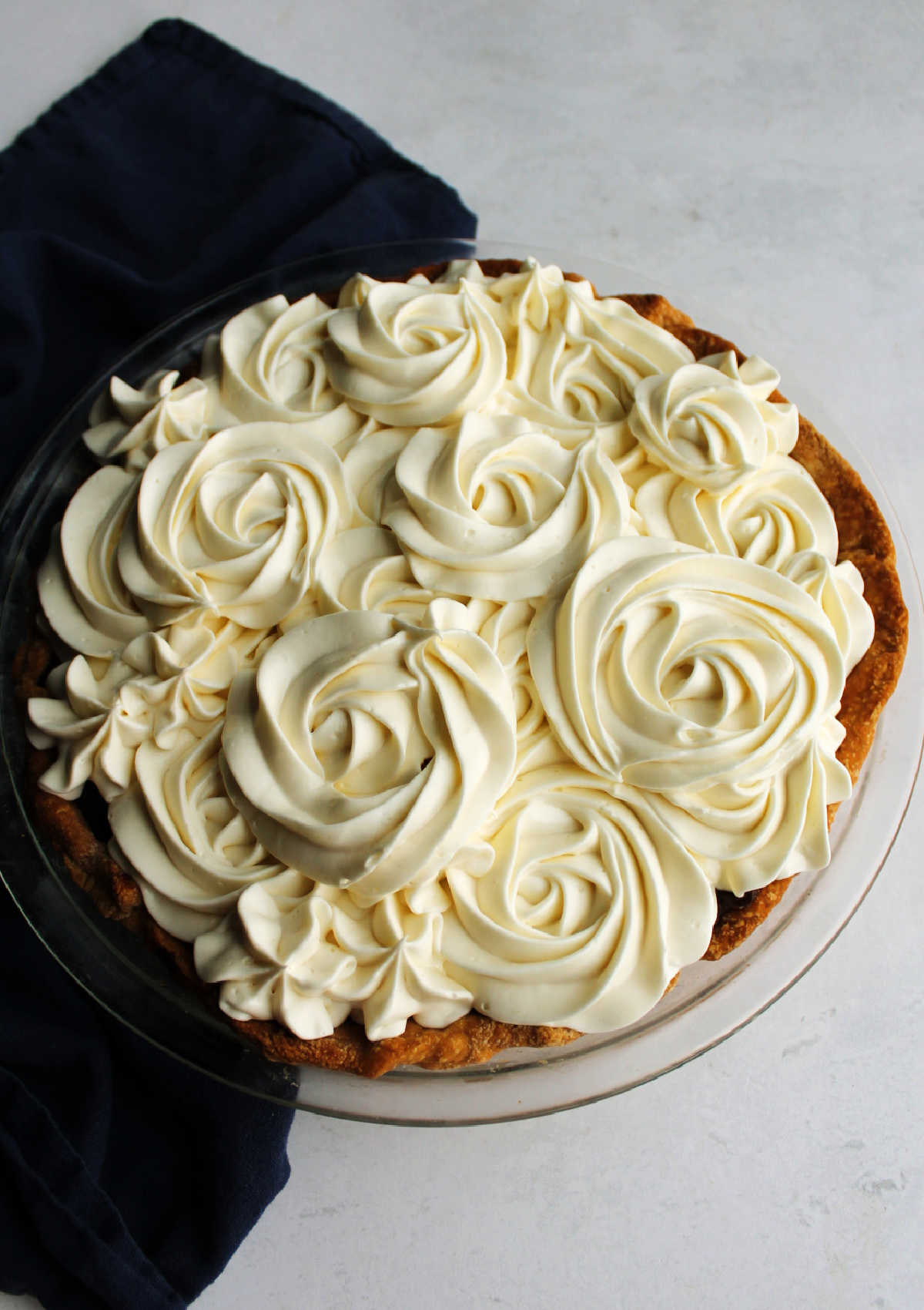 Whole homemade chocolate pie topped with swirls of cream cheese whipped cream.