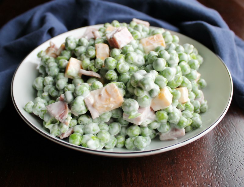 close up of a serving bowl of lightened up pea salad with cheese and ham