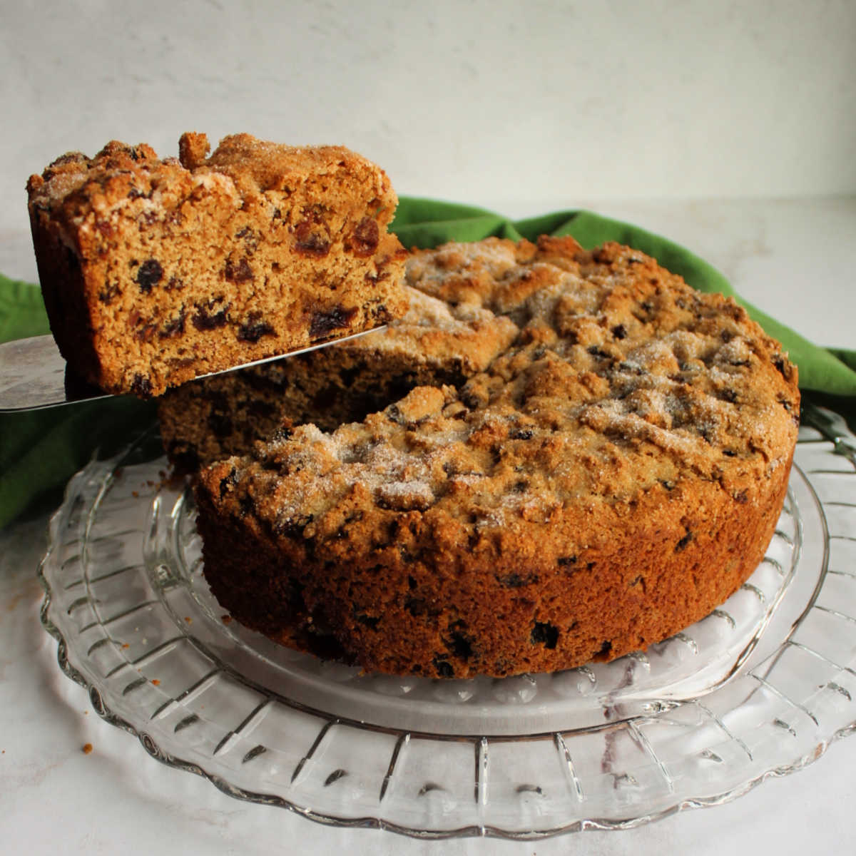 First slice of Irish tea brack being lifted out of round cakelike loaf, showing lots of fruit in the interior.