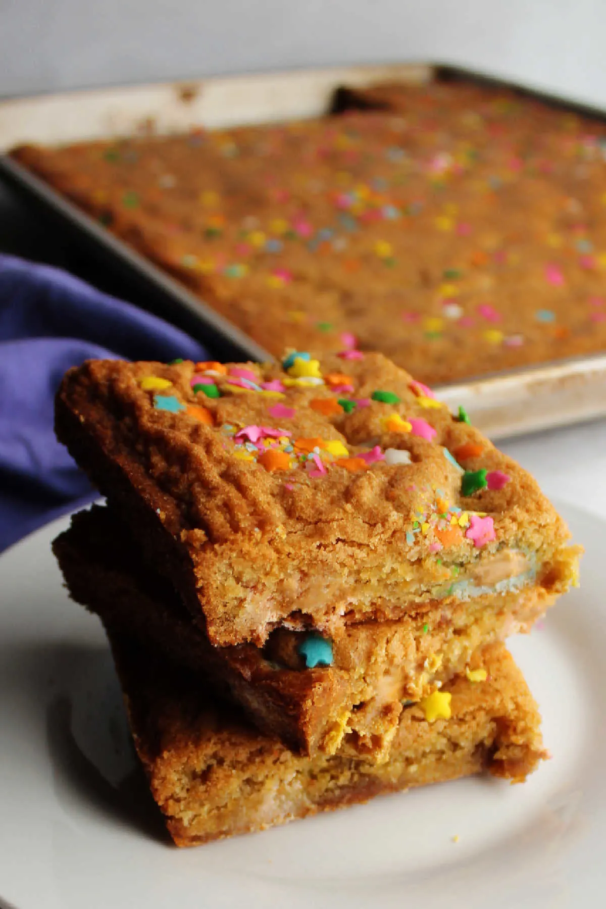 Stack of easter egg blondies on plate in front of pan.