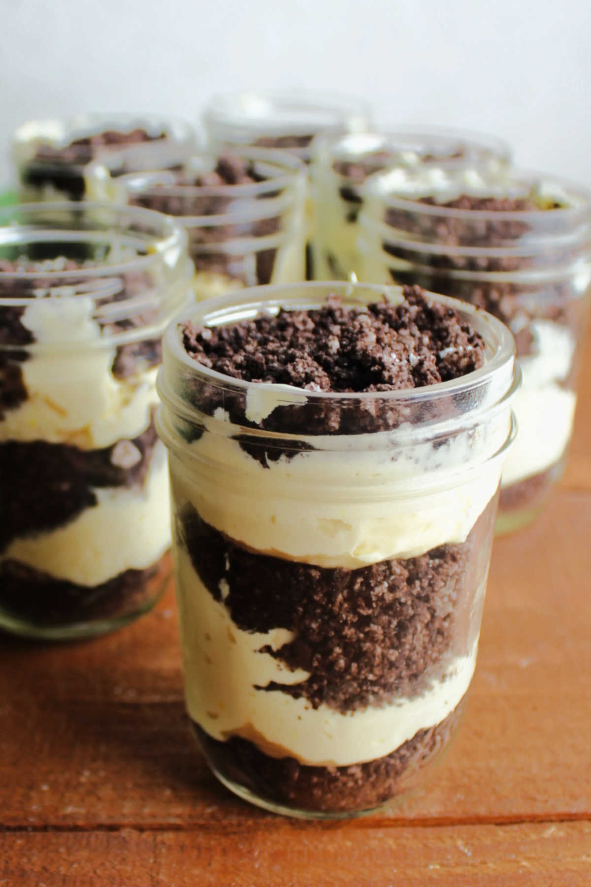 Layers of vanilla pudding and Oreo crumbs in jars for individual sized dirt puddings.