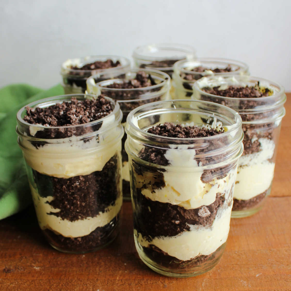 Layers of vanilla pudding mixture and chocolate oreo crumbs layered in jars to make dirt pudding.