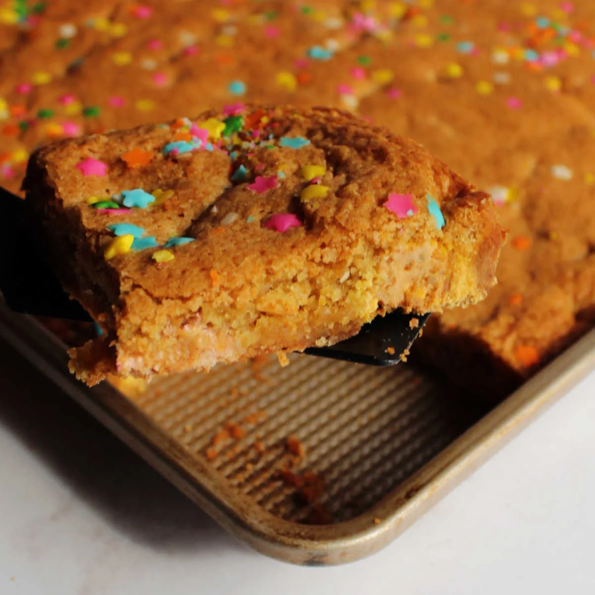 Spatula lifting slice of easter egg blondies out of pan.