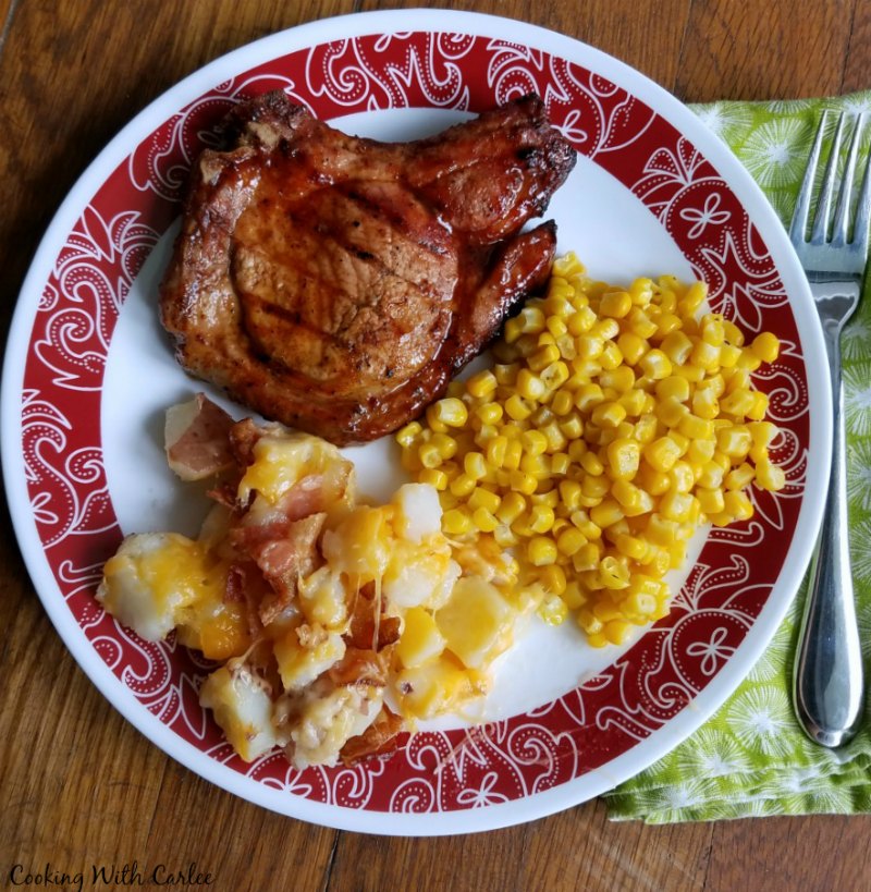 dinner plate with cheese and bacon potato bake, pork chop and corn.