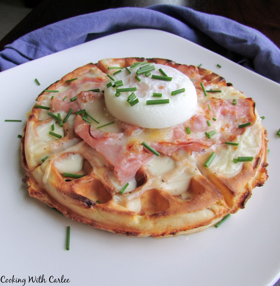 croque madame waffle topped with white sauce, ham, cheese and a poached egg