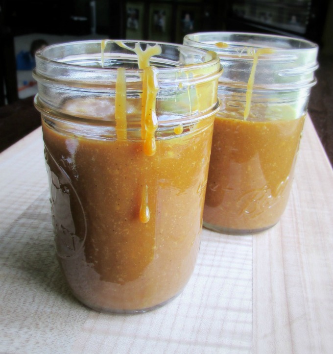 two jars of golden goat's milk cajeta with a drip running down the side of the front jar.