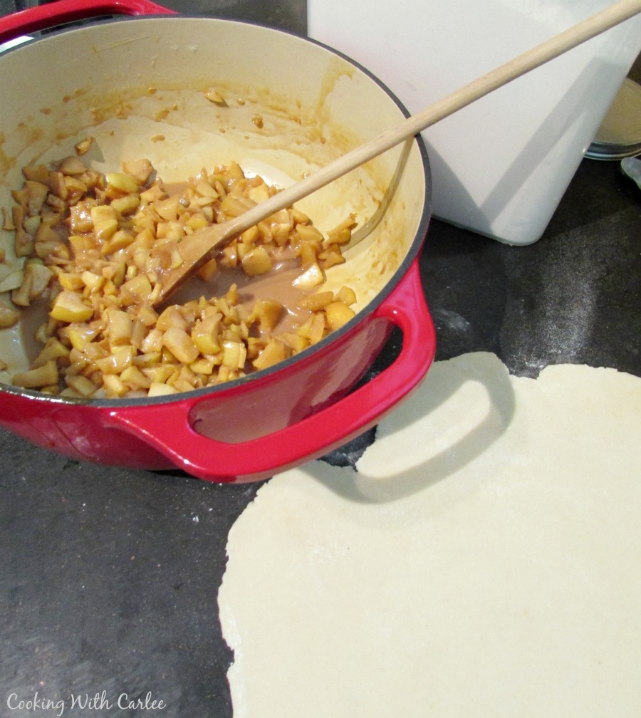 apple and caramel-ly cajeta mixture in pan next to empanada dough.