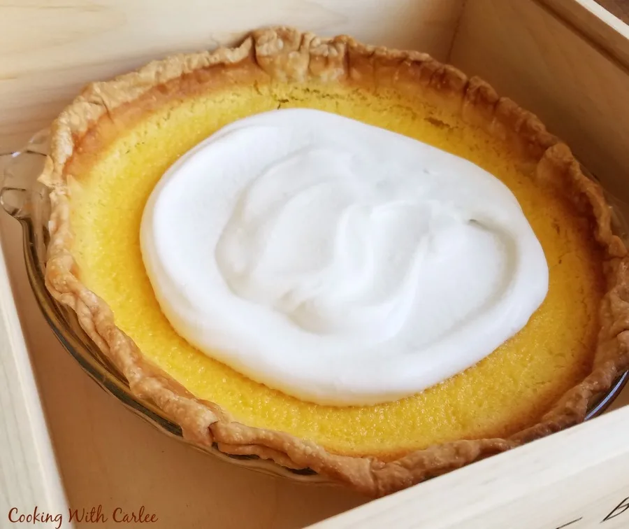 whole lemon pie with cloud of honey whipped cream in the center.