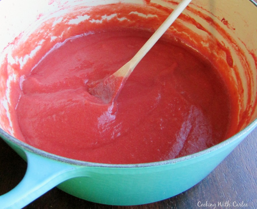 Cast iron pot full of pink strawberry rhubarb sauce.