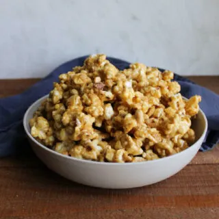 Bowl piled high with crispy caramel corn with peanuts.