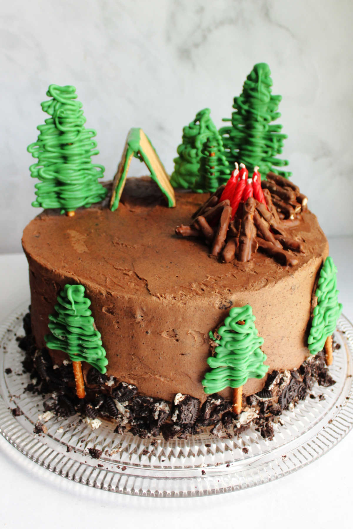Camping cake made with cookies and cream cake coated with chocolate Oreo frosting and camping decorations