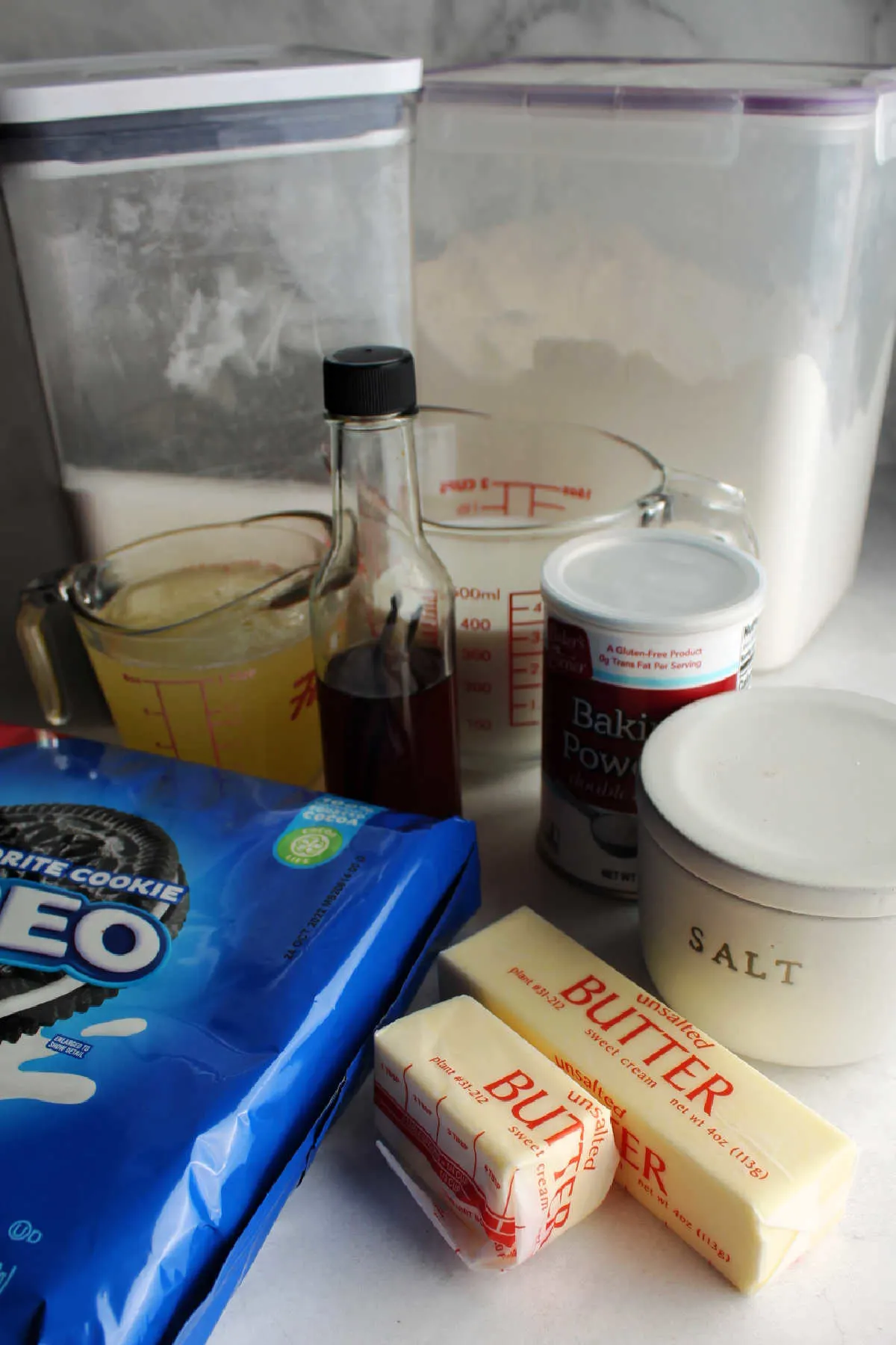 Ingredients for cookies and cream cake, including butter, sugar, flour, vanilla, egg whites, milk and Oreos.