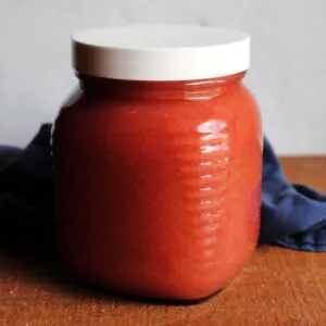 Quart jar filled with homemade strawberry rhubarb applesauce showing pink color.