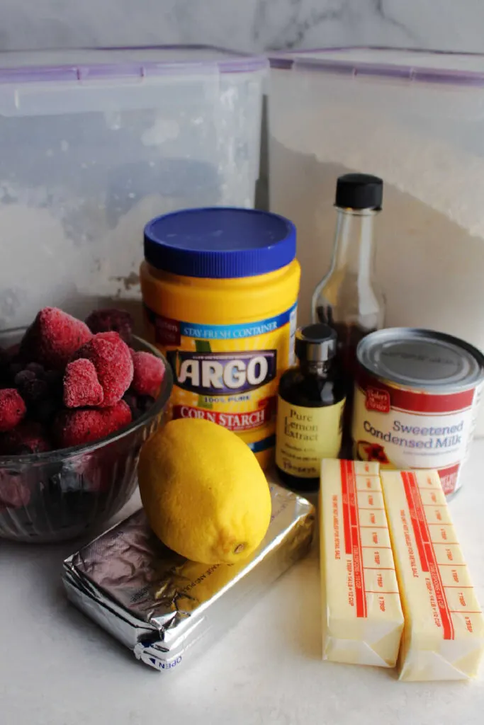Ingredients ready to be made into pie with cookie crust, lemon filling and berry topping.