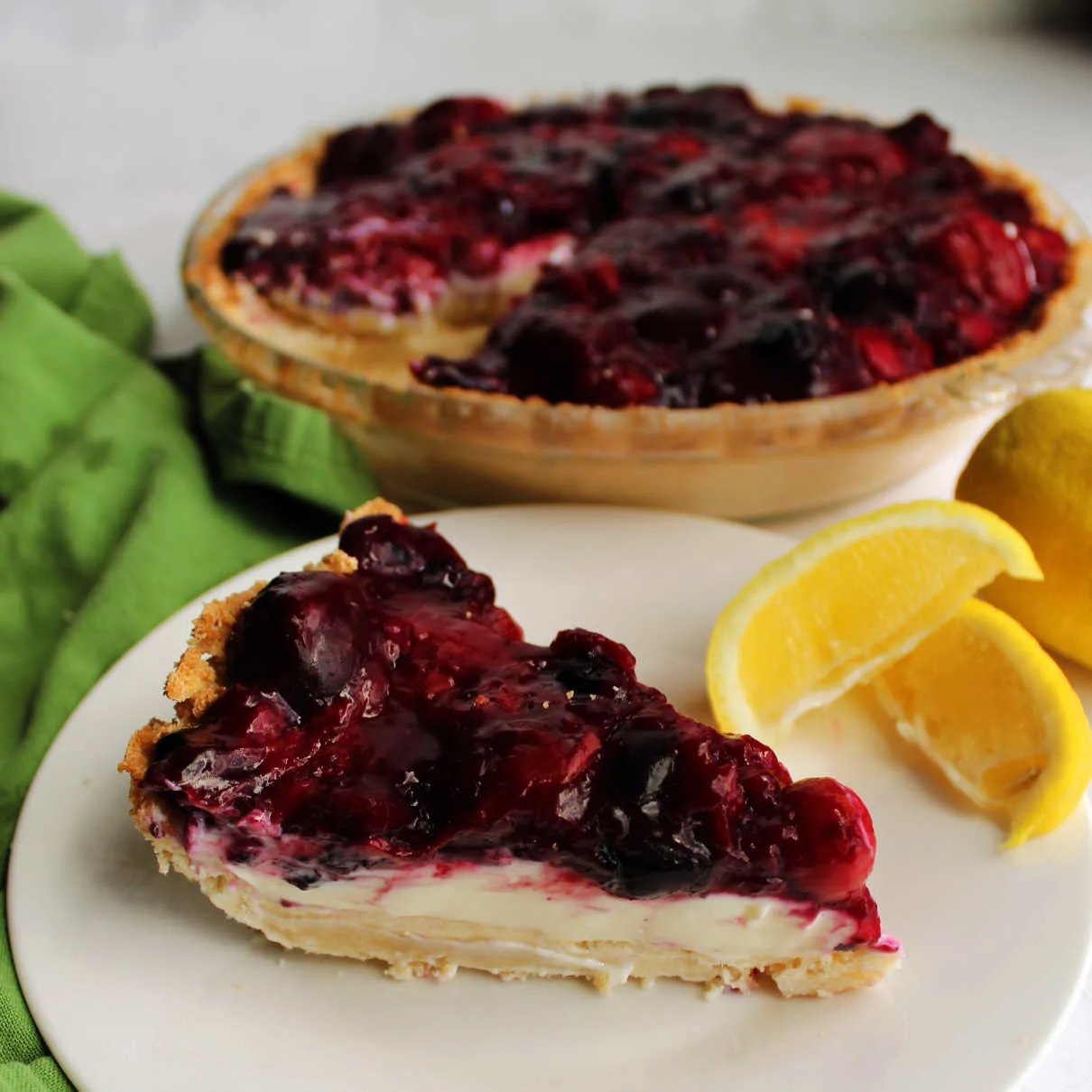 Slice of pie with creamy lemon filling and thick berry topping.