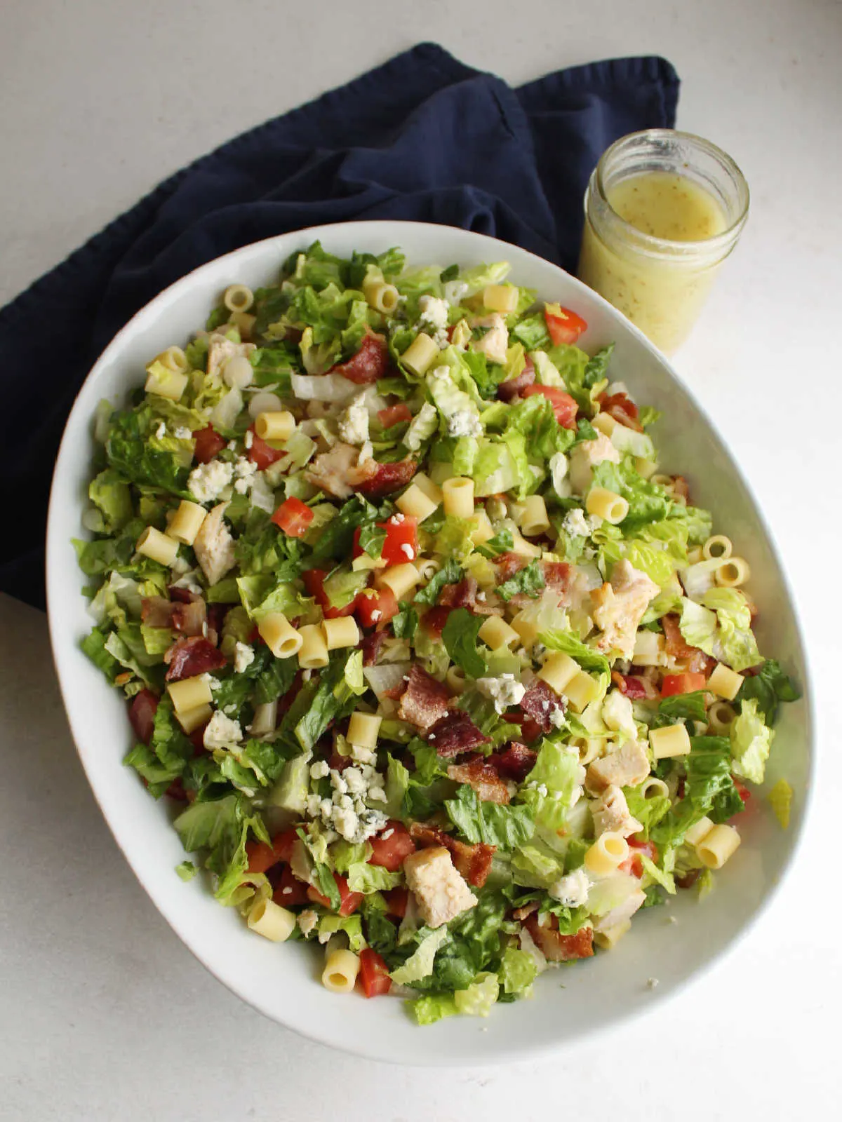 Tossed chopped salad with jar of vinaigrette nearby.