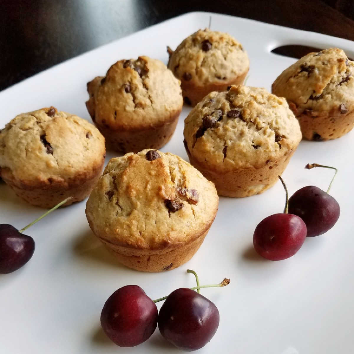 cherry chip muffins on platter with fresh sweet cherries.