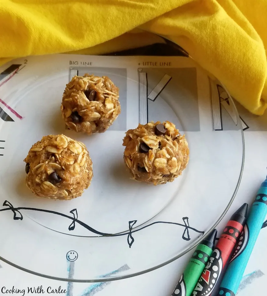 The peanut butter, banana and honey oatmeal balls with chocolate chips on glass plate next to coloring sheet and crayons.