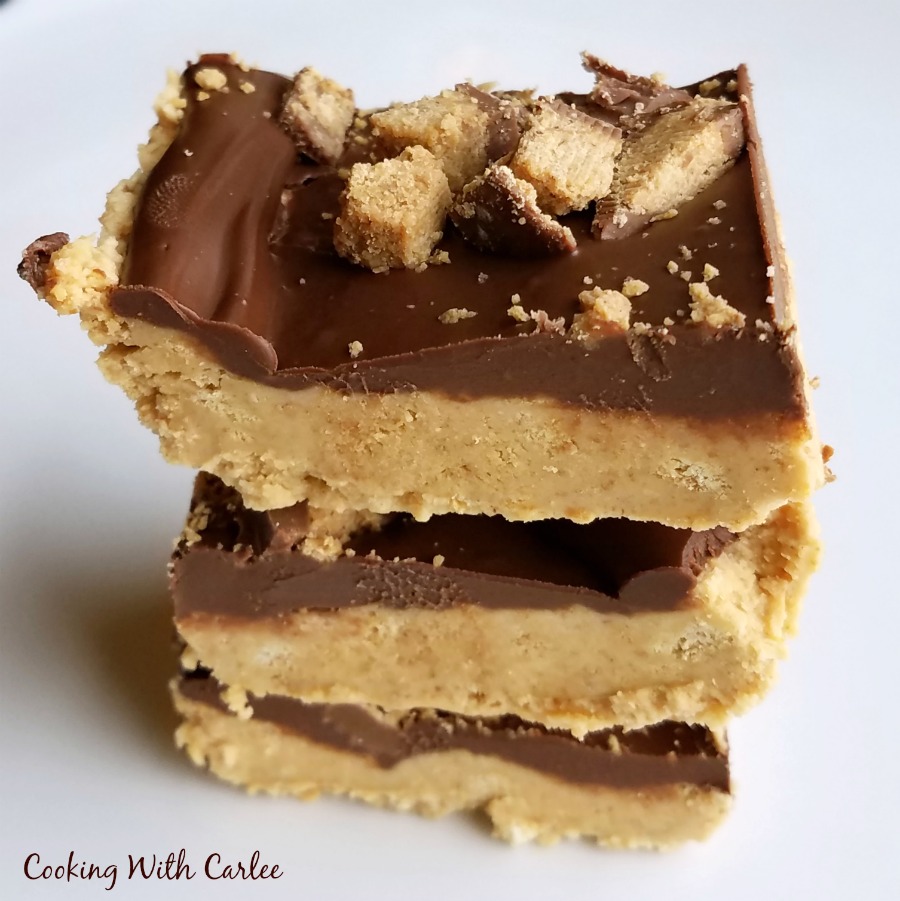 close stack of no bake peanut butter bars with chocolate topping and chopped peanut butter cups on top