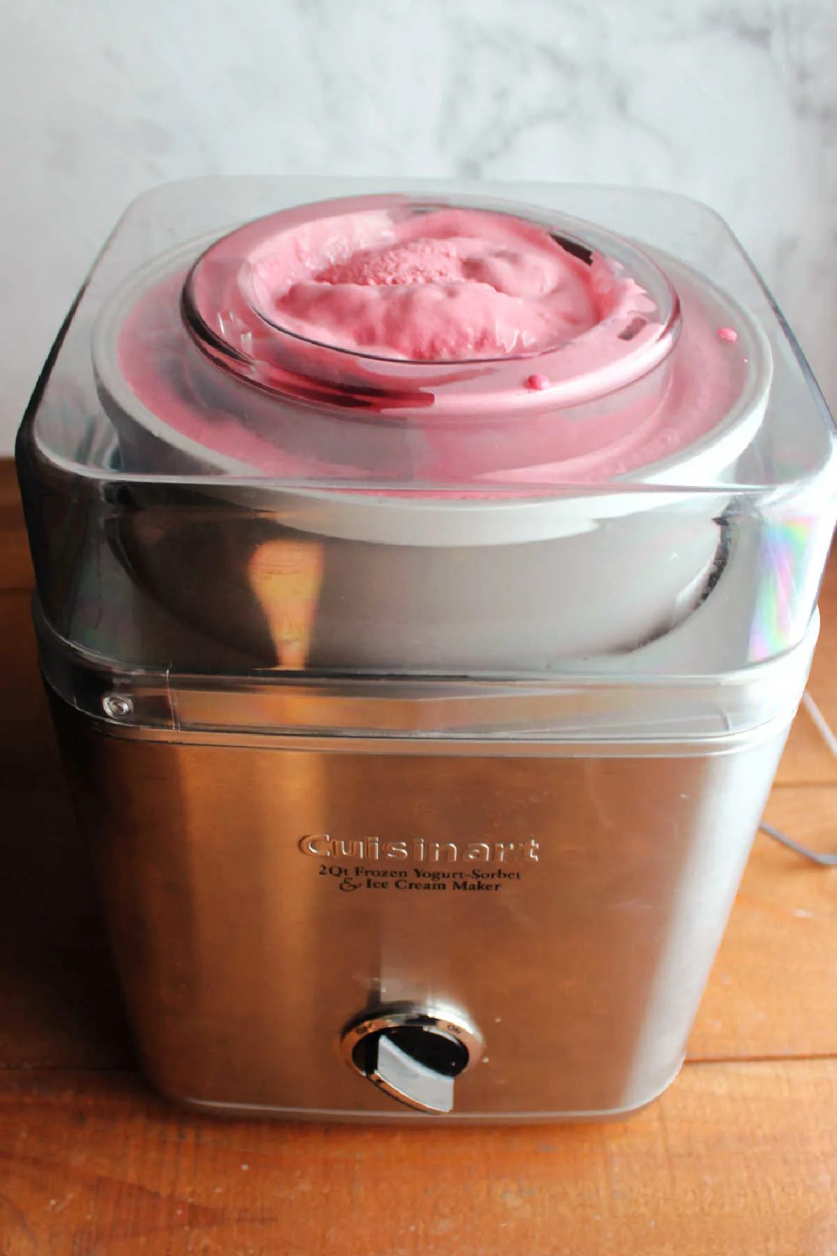 Ice cream maker filled with pinkish purple blackberry ice cream, ready to be transferred to storage containers and frozen.