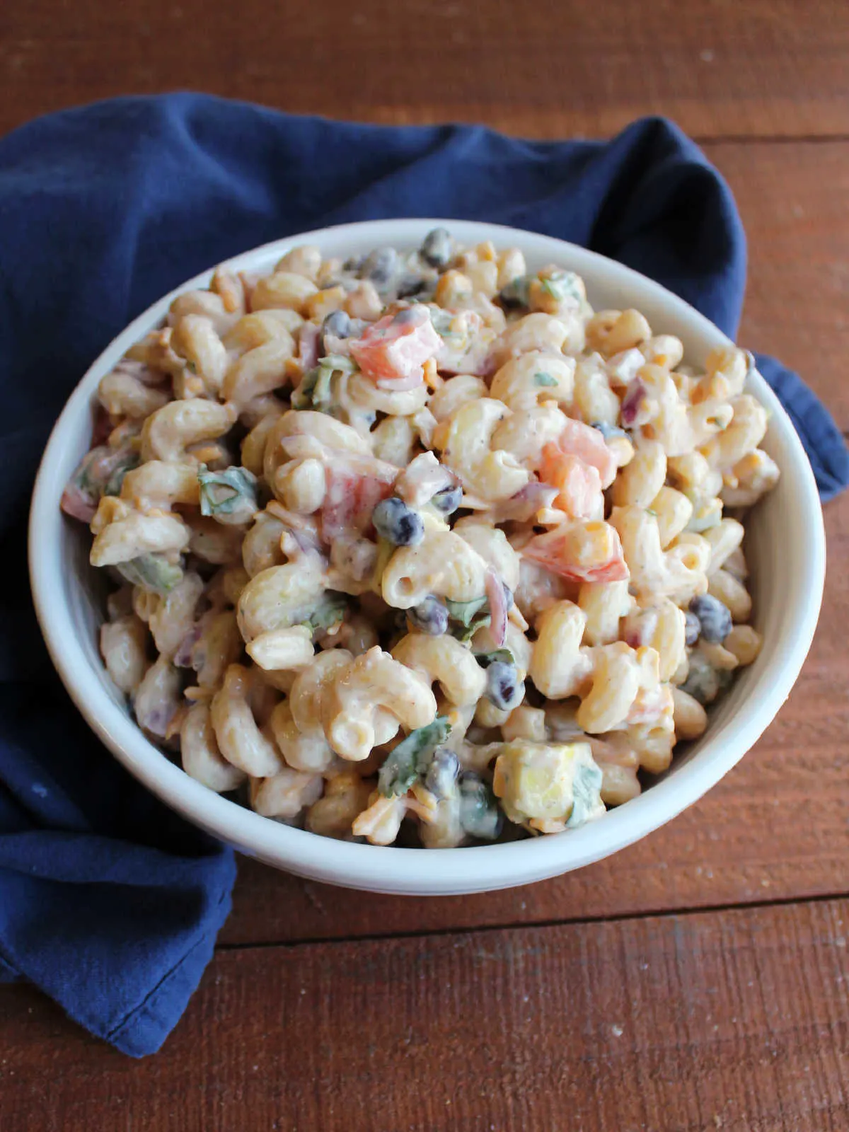 Serving bowl filled with creamy bbq ranch pasta salad loaded with corn, black beans, veggies and cheese.