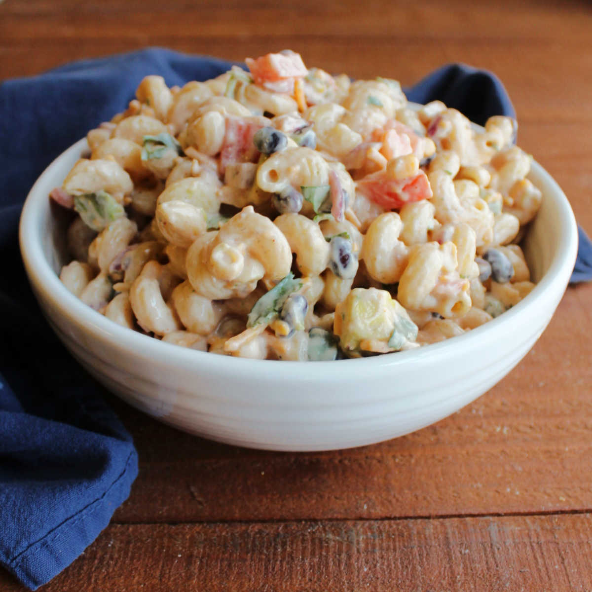 Serving bowl filled with bbq ranch macaroni salad with black beans, tomatoes, corn and more.