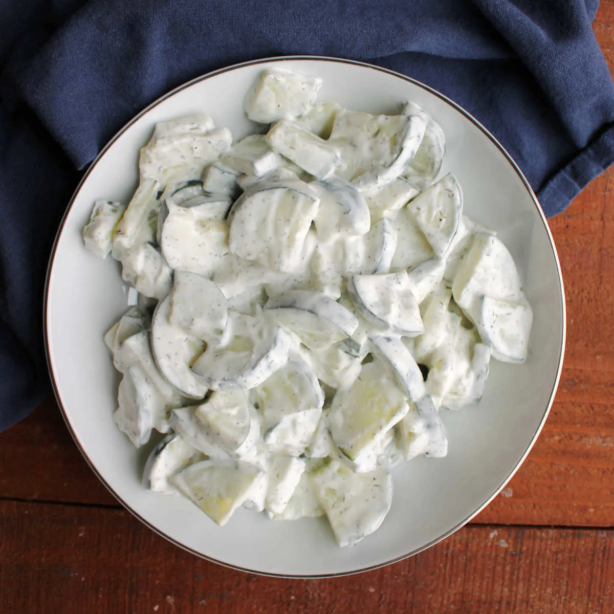 Serving bowl filled with creamy cucumber salad with a sour cream and dill dressing.