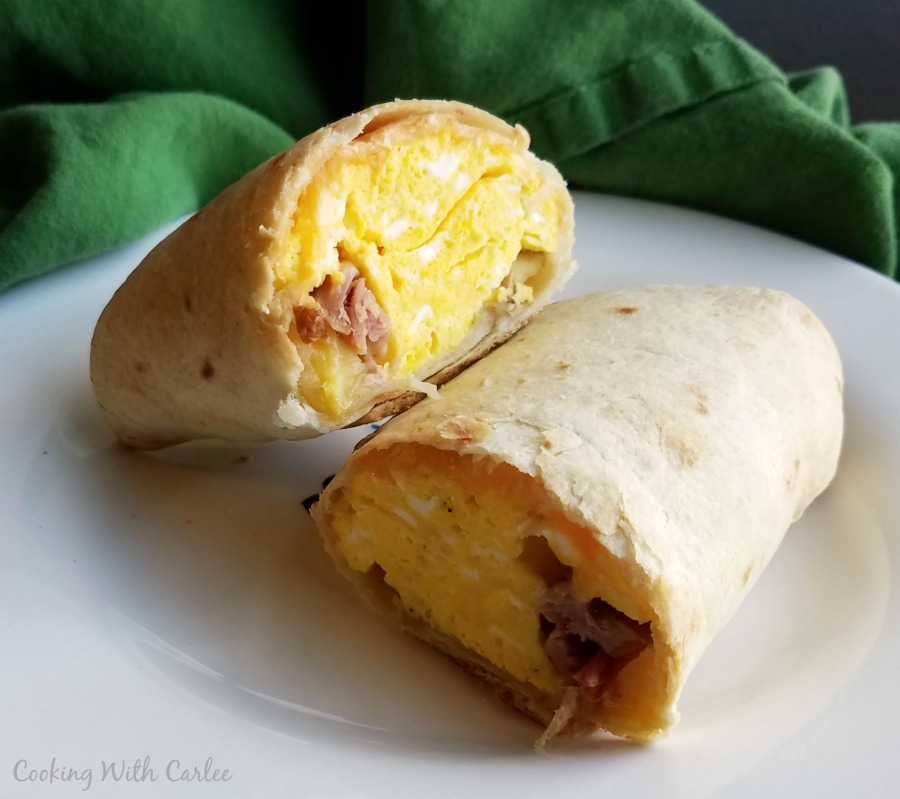 breakfast chimichanga cut in half to show crispy exterior and ham, egg, cheese and potato filling inside.