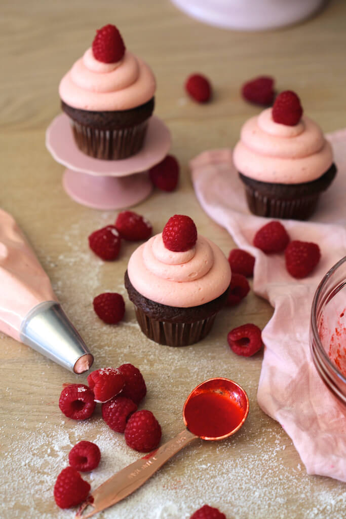 cupcakes topped with raspberry frosting and fresh raspberries