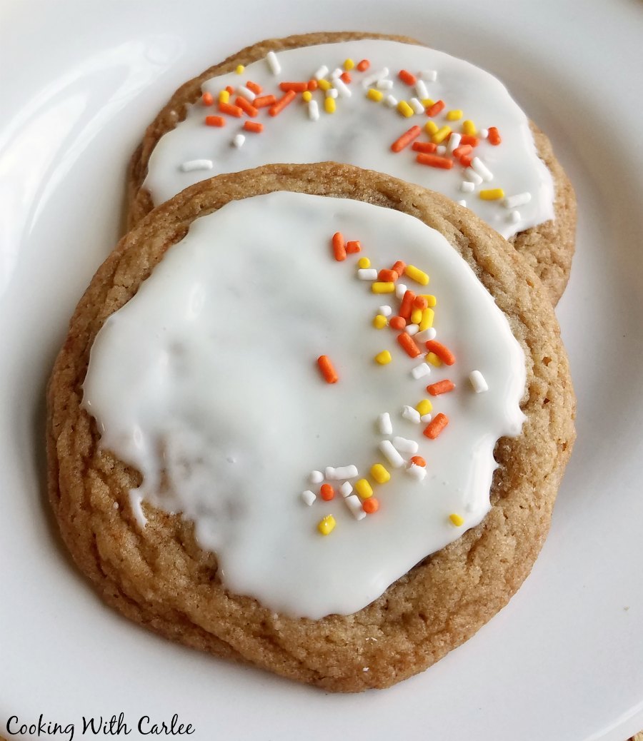 two glazed chewy maple cinnamon cookies with a smattering of sprinkles on them.