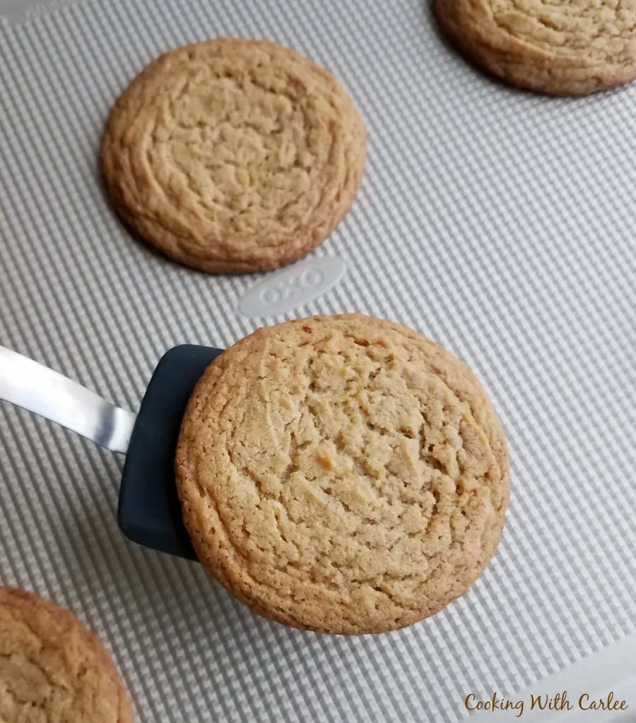 large maple cinnamon cookies fresh from oven with spatula taking cookie off tray.