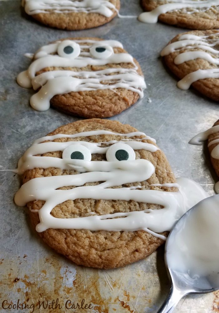 tray of maple cinnamon cookies with drizzles of white glaze and eye ball candies to make them look like mummies.