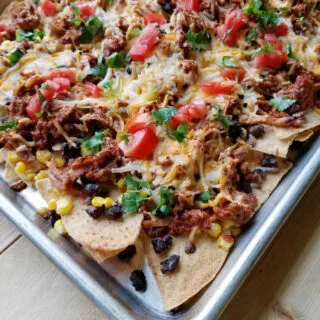 sheet pan loaded up with bbq pulled pork nachos and tons of fun toppings.