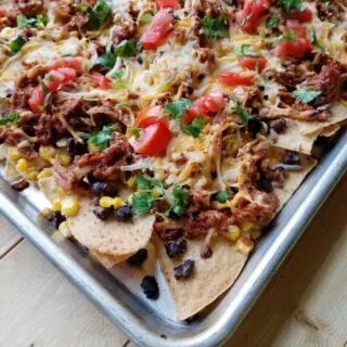 Sheet pan filled with tortilla chips, pulled pork, cheese etc.