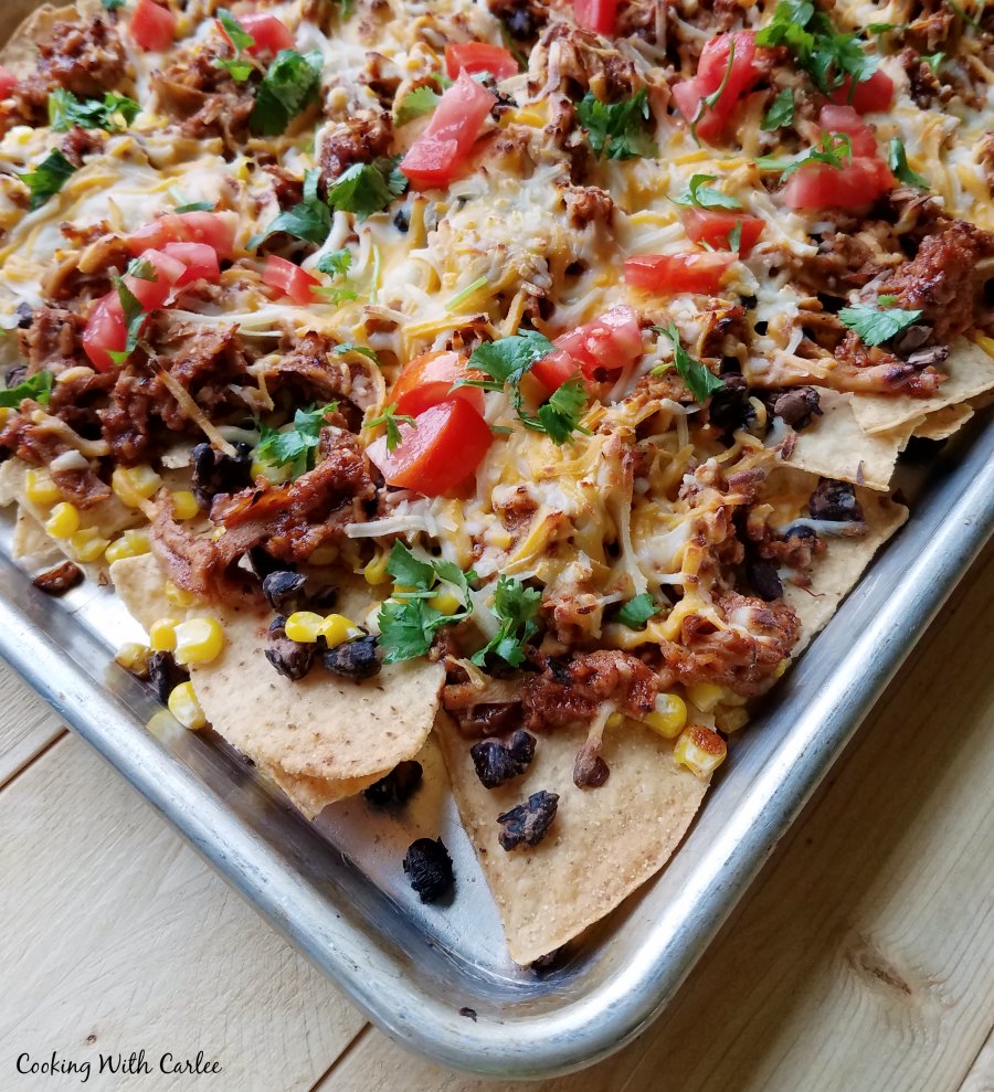 sheet pan loaded up with bbq pulled pork nachos and tons of fun toppings