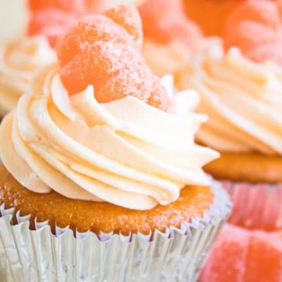 Orange crush frosting topped cupcakes with candied orange slices on top.