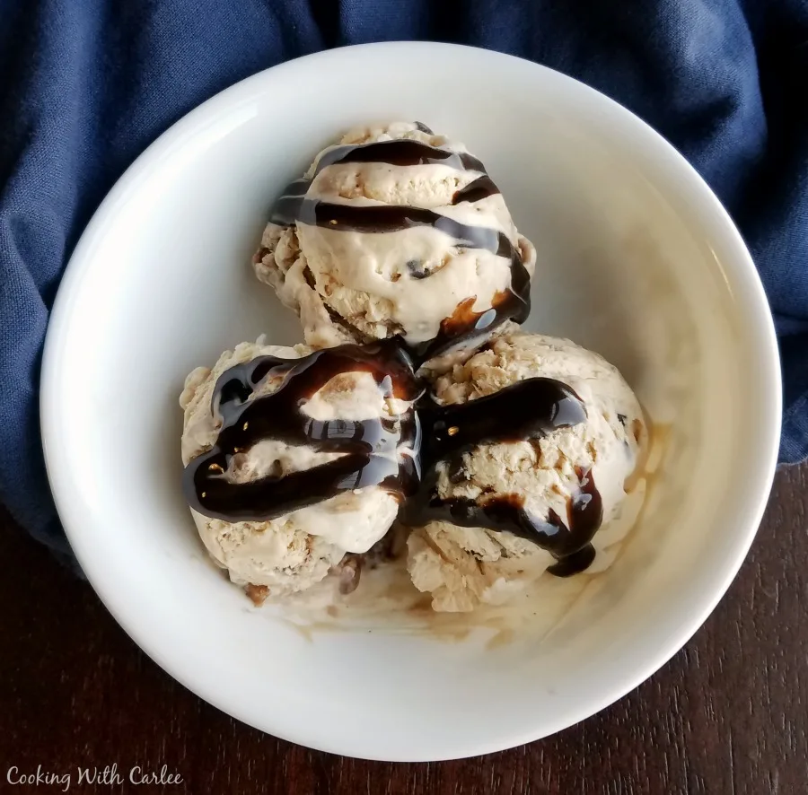 three scoops of ice cream drizzled with hot fudge.
