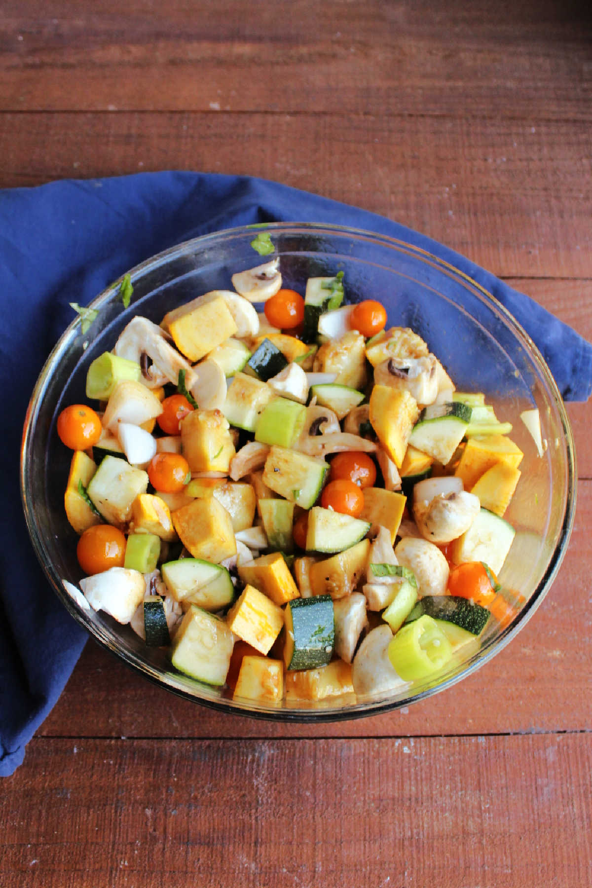 Chunks of fresh vegetables in mixing bowl with marinade.